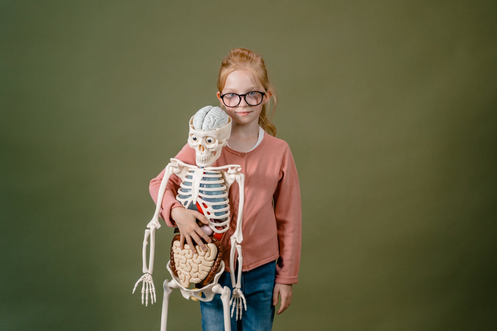 a girl holding a model of a skeleton